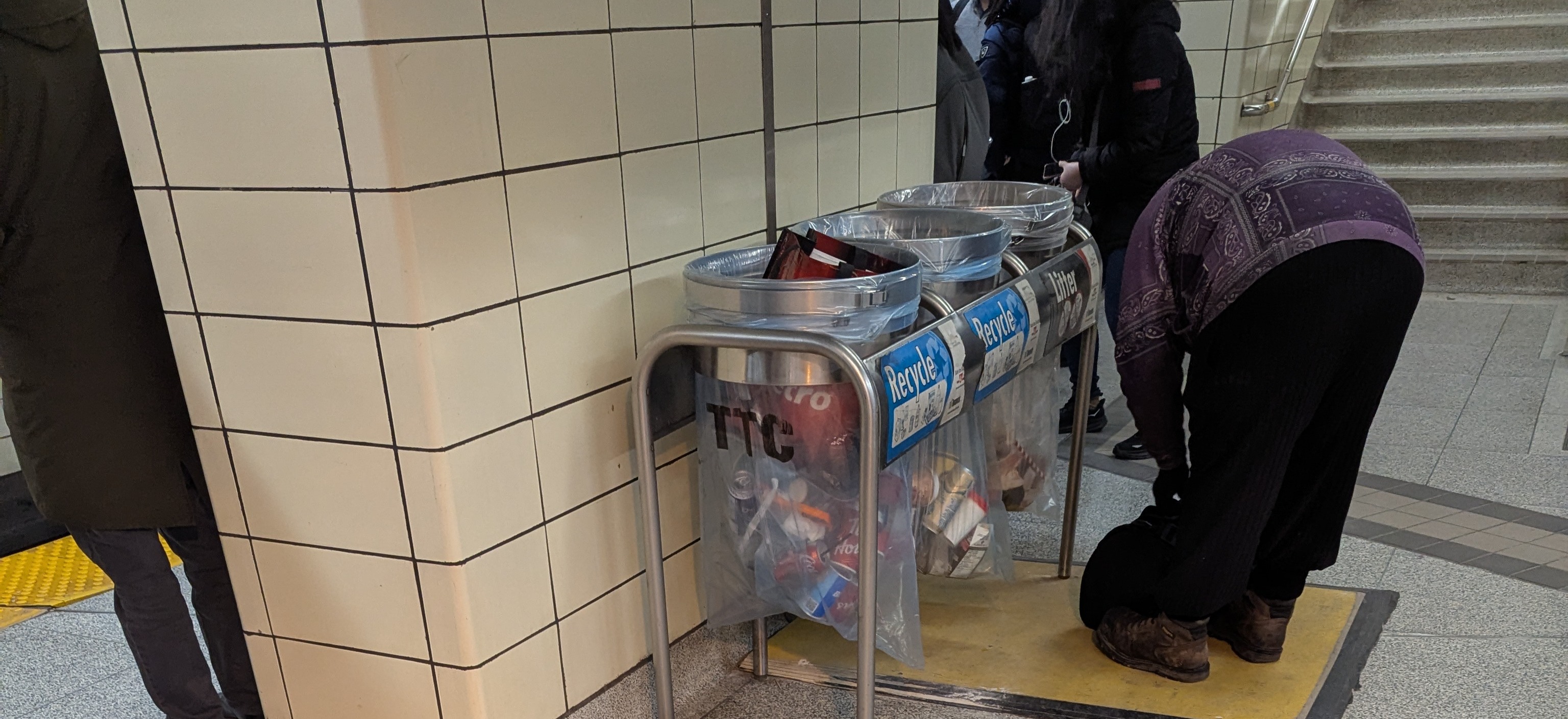 Man searching inside of recycling bins.